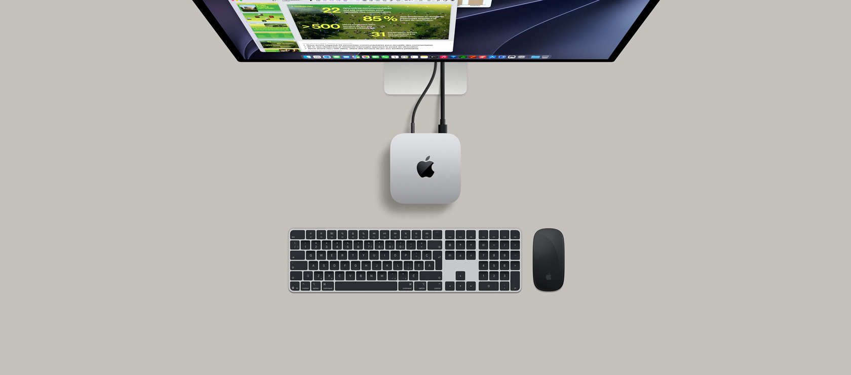 Vue du dessus d’un Mac mini, aluminium argent, coins arrondis, logo Apple noir brillant centré, branché à un câble, Studio Display partiellement visible au-dessus, l’écran affichant l’app Calendrier, une présentation Keynote et un graphique à barres, tous ouverts, le clavier Magic Keyboard avec pavé numérique, la souris Magic Mouse visible sous le Mac mini