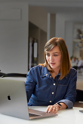 An Apple Support and Service team member working on a MacBook in a common area.