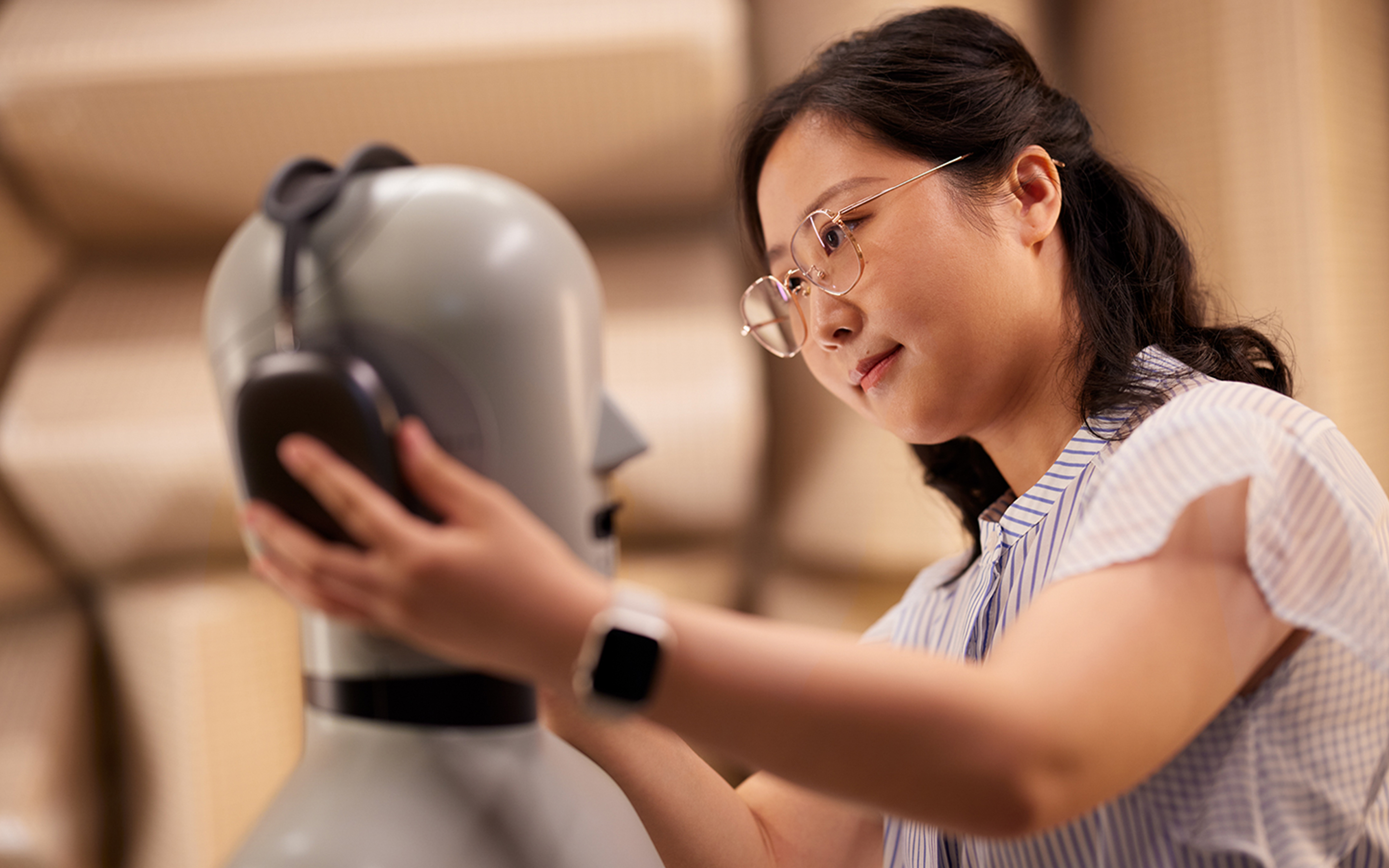 An Apple Hardware team member fitting AirPods Max headphones on a mannequin in a lab.