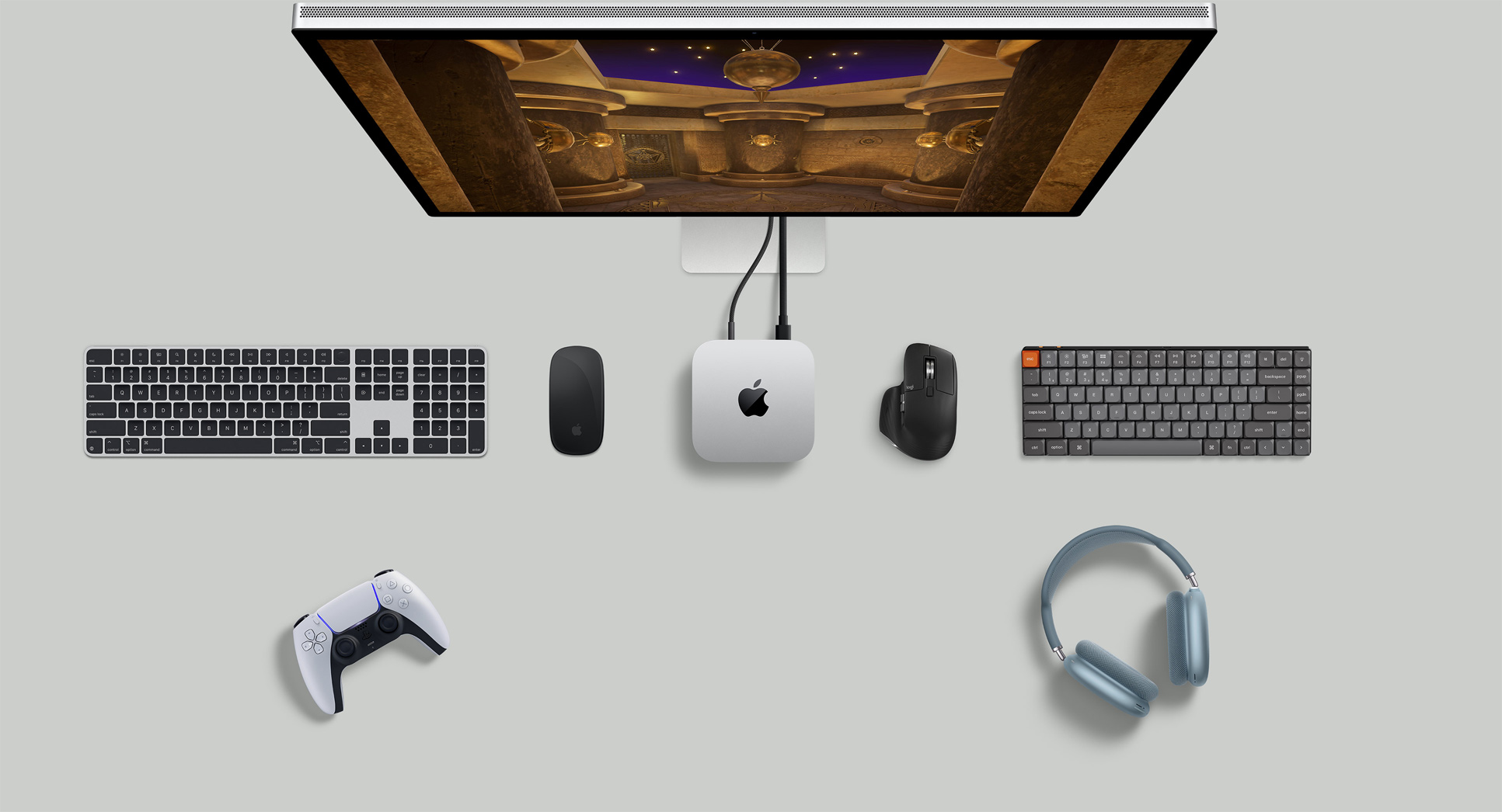 Felülnézeti kép egy íróasztalról, amelyen egy Mac mini, egy Studio Display, vezeték nélküli billentyűzetek, vezeték nélküli egerek, egy játékkontroller és egy AirPods Max fejhallgató van