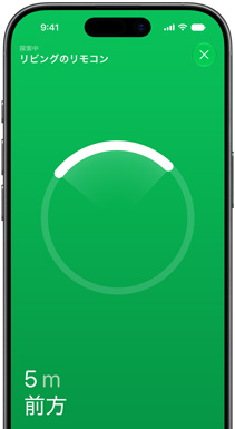 iPhoneの画面上の「探す」アプリ。リビングルームのSiri Remoteを探しているとテキストで示され、円形のロケーターリングの光る部分が方向を指している。5メートル前方にあるとテキストで示されている