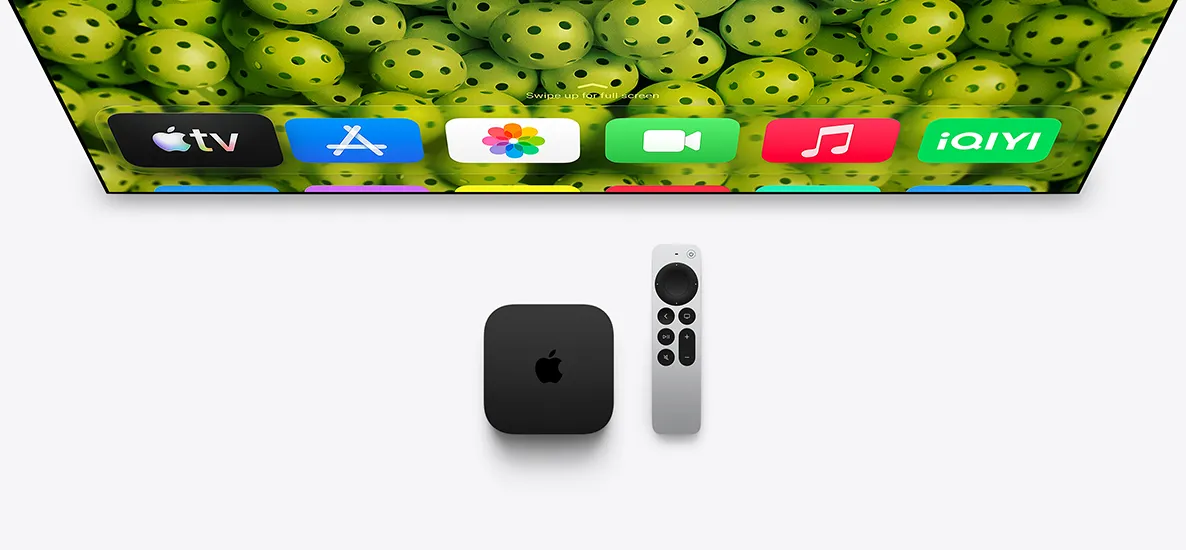 Apple TV 4K 和 Apple TV Remote 置於電視螢幕下方，螢幕顯示主畫面，展示最高一列的 app 圖示，背景為綠色匹克球