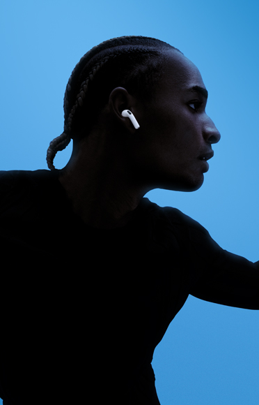 Eine Person trägt AirPods 5, die Arme sind ausgebreitet, farbiger Hintergrund