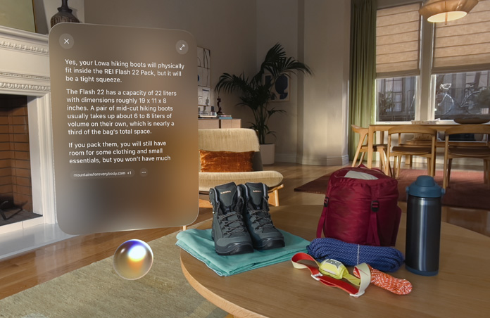 Apple Vision Pro Ansicht, eine Unterhaltung mit Siri darüber, ob die Wanderstiefeln in den Rucksack passen, schwebt über Siri und links von einem Paar Wanderstiefeln und anderer Outdoor-Ausrüstung