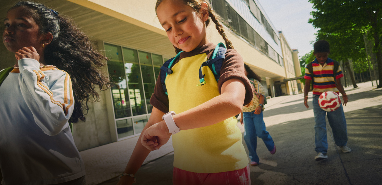 ภาพระยะใกล้ของเด็กที่สวมเป้และกำลังใช้ Apple Watch