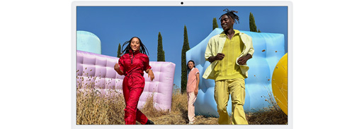 Tre personer i farvestrålende outfits, som er omgivet af farverige oppustelige figurer